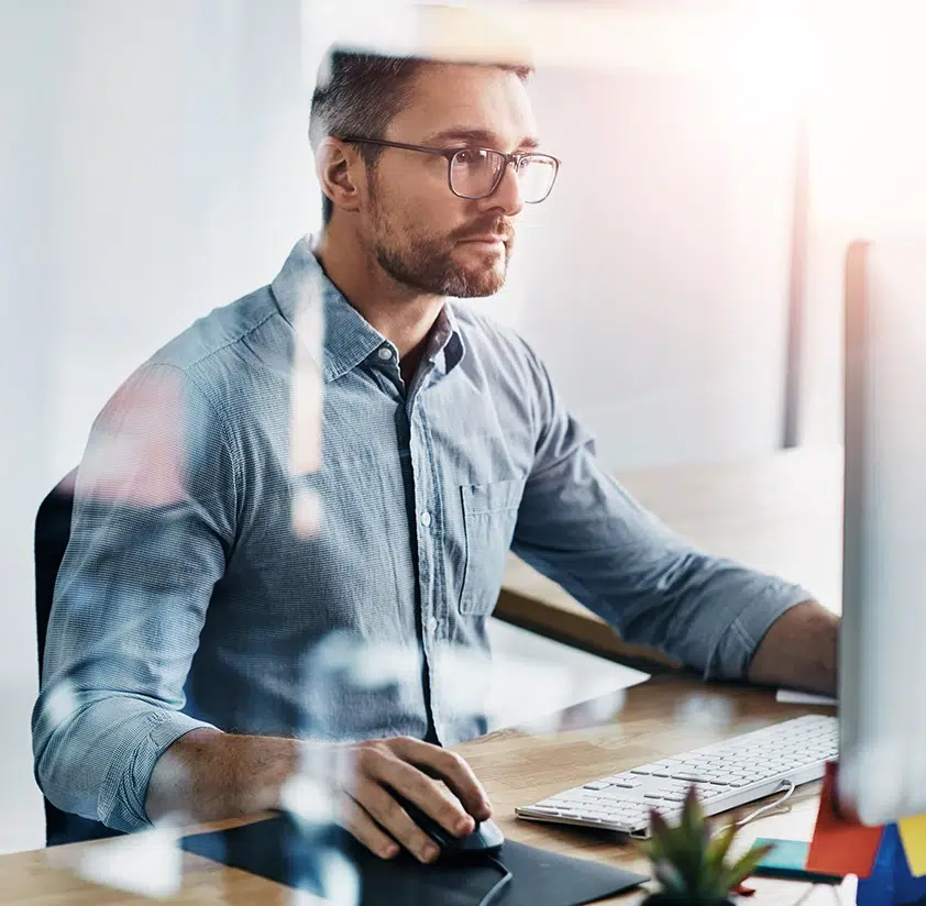 Mann mit Brille arbeitet konzentriert am Computer im Büro.